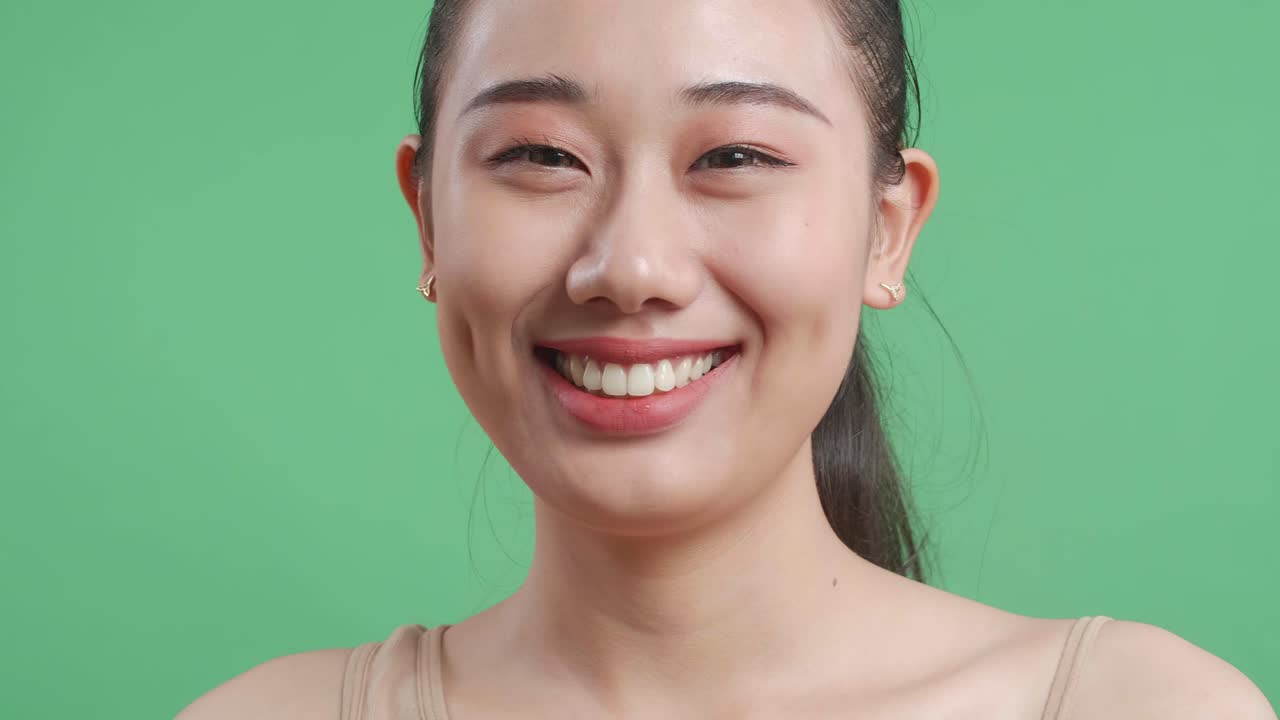 초록색 스크린 앞에서 메이크업으로 미소 짓는 여자