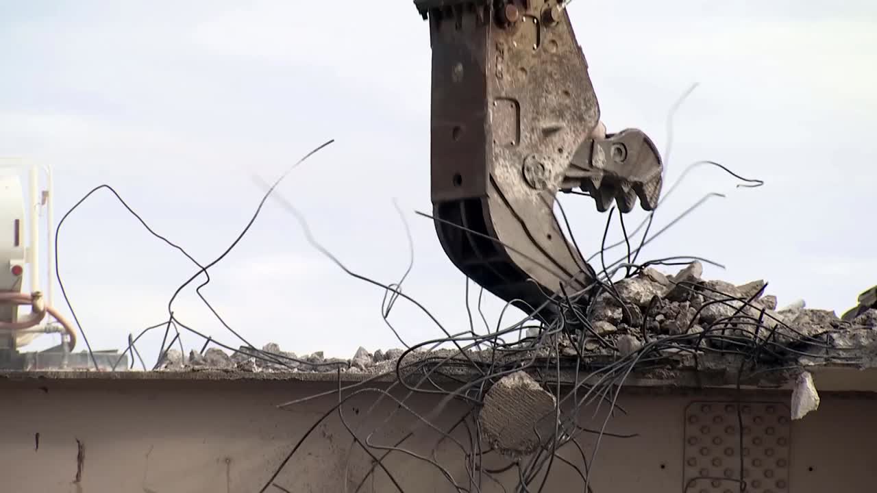 금속 굴착기 클로가 교량 현장에서 콘크리트를 제거합니다.