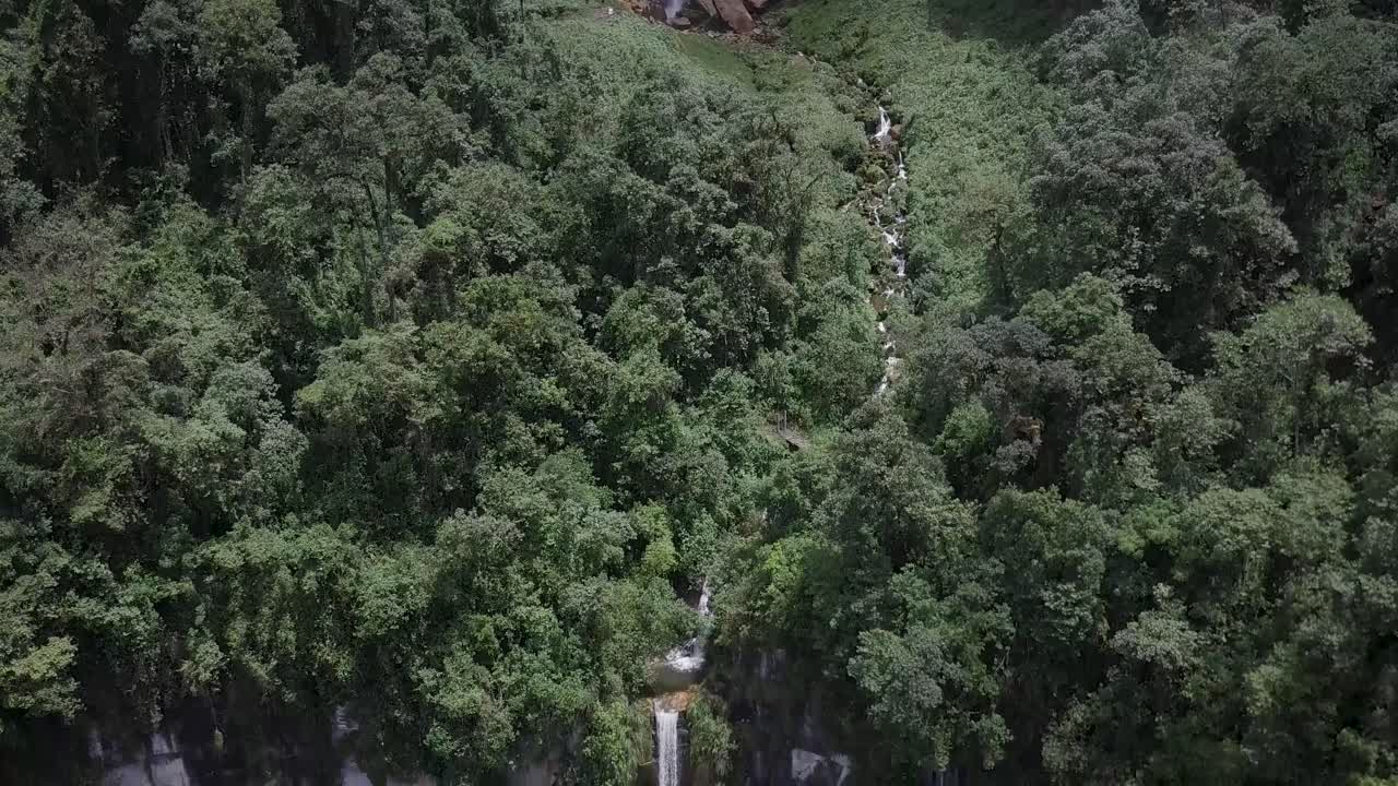 vista aérea de una alta cascada que cae en cascada por un acantilado rodeado de exuberante vegetación verde