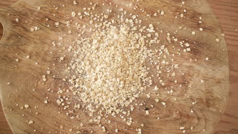 tirando copos de avena en un montón sobre fondo de madera, vista de arriba hacia abajo, cámara lenta
