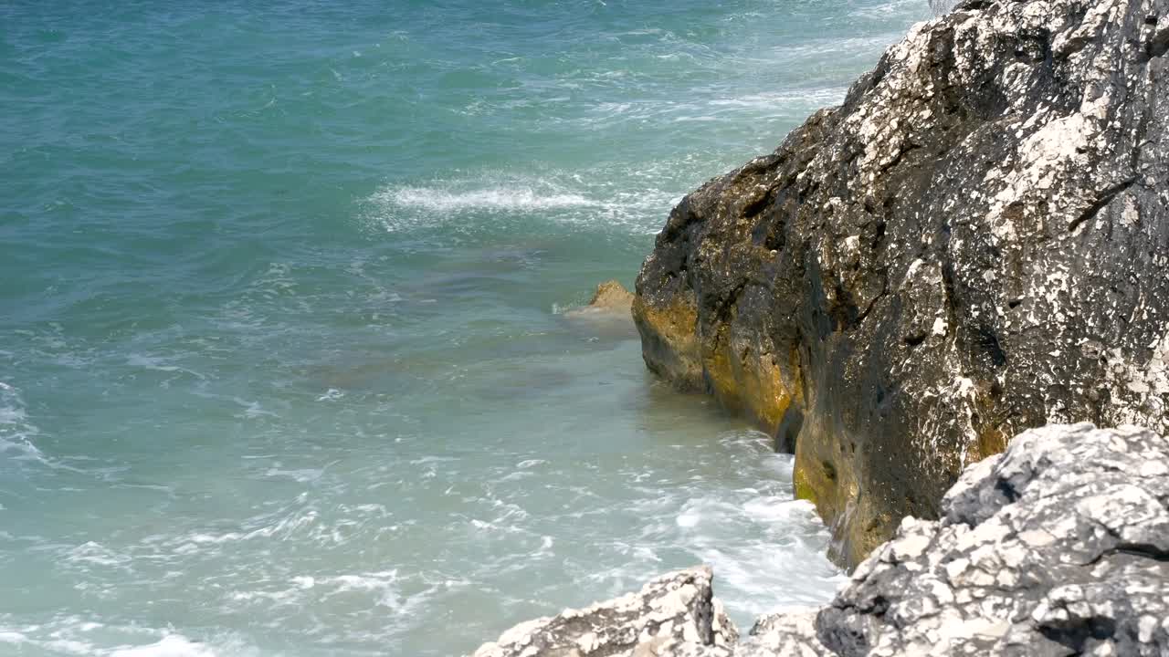 Primo piano su onde spumeggianti che si infrangono contro una scogliera rocciosa sull'isola di Corfù