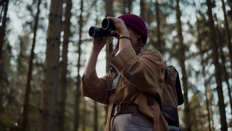 female tourist with backpack searching through binoculars