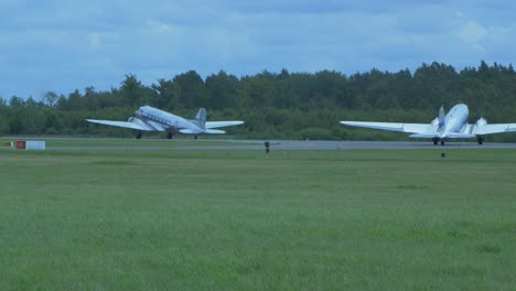 dos plata y azul douglas dc3 actúa en el espectáculo aéreo internacional del báltico, gravando en la pista, vista desde el suelo, tiro de 4k de mano