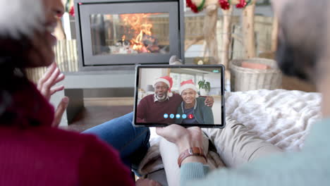 Happy-diverse-couple-and-senior-parents-having-christmas-tablet-video-call,-slow-motion