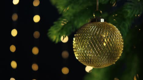 golden metal ball close-up hanging on spruce branch. christmas sustainable bauble. slow motion. christmas or new year background. selective focus