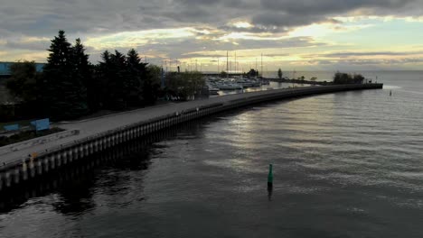 Drone-Elevándose-Sobre-El-Puerto-De-Mississauga-Con-Un-Amanecer-Sobre-El-Lago-Ontario