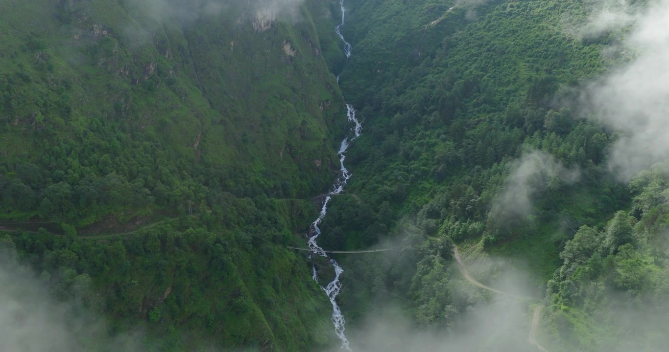 Panchpokhari, Sindhupalchowk, Nepal, drone afslører den hvide gletsjerflod og den omkringliggende grønne fyrreskov samt den store bjergdal under de tykke monsunskyer