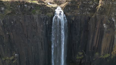 Close-up-backwards-drone-dolley-shot-of-water-falling-down-over-the-mealt-falls-in-Scotland