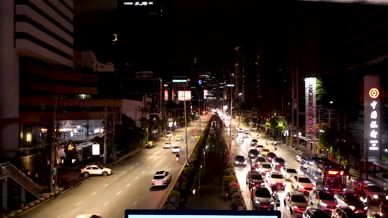 Busy urban street with heavy nighttime traffic, city lights, and elevated perspective, steady camera