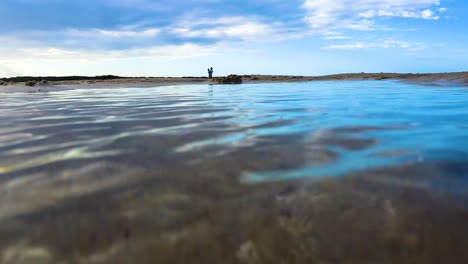 A-camera-skims-across-a-crystal-clear-pool-of-water