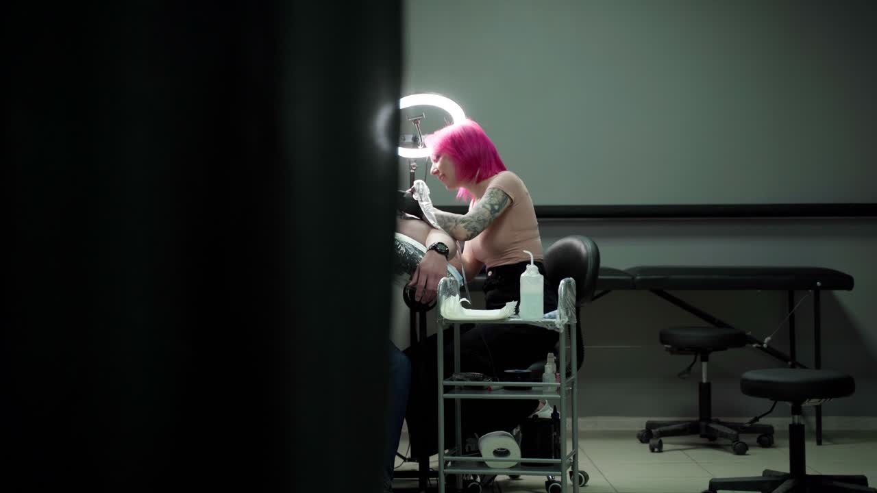 스튜디오에서 기계로 어깨에 문신을 칠하는 여성 문신작가