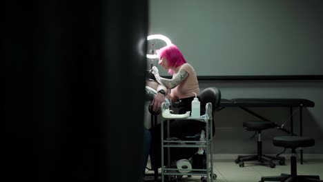 tatuadora femenina pintando un tatuaje en el hombro con una máquina en el estudio