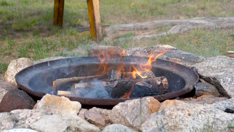 Mesmerizing-Daytime-Fire-in-Wheel-Barrel-Firepit-Surrounded-by-Rocks---Burning-Logs-180fps-Slow-Motion