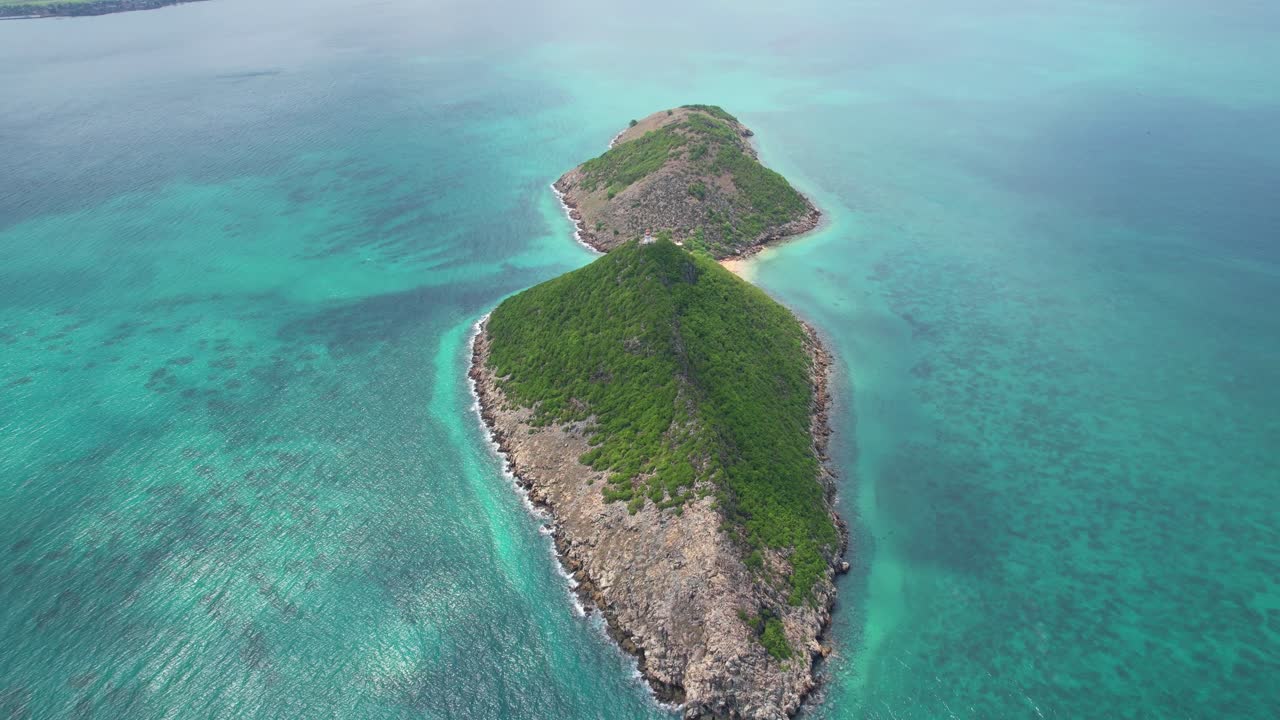 Eine cineastische Drohnenaufnahme gleitet in Richtung Ilhéu das Cabras vor der Küste von São Tomé und enthüllt dramatische Vulkanklippen, die aus leuchtend türkisfarbenem Wasser emporragen. São Tomé, Afrika
