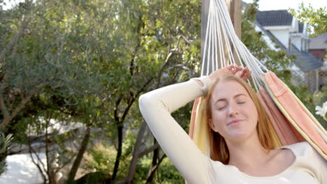 relaxing in hammock, woman enjoying sunny day outdoors in backyard