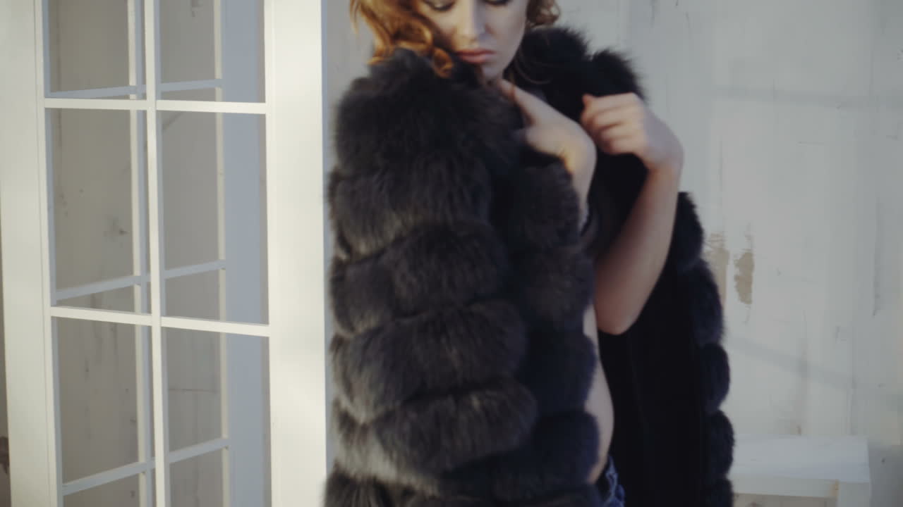 A young sexy woman takes off her coat and remains in her underwear.