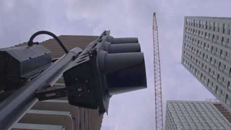 modern cityscape skyline skyscraper building construction crane and traffic light looking up against cloudy sky, smart city 5g ai connection concept