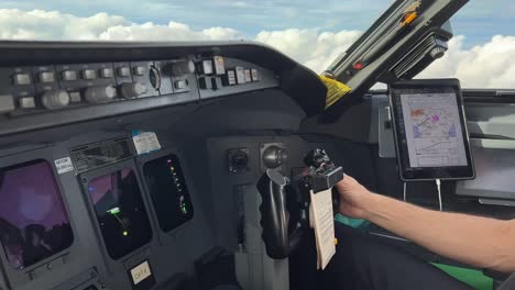 copilot handling flight controls of a modern jet cockpit overflying some clouds