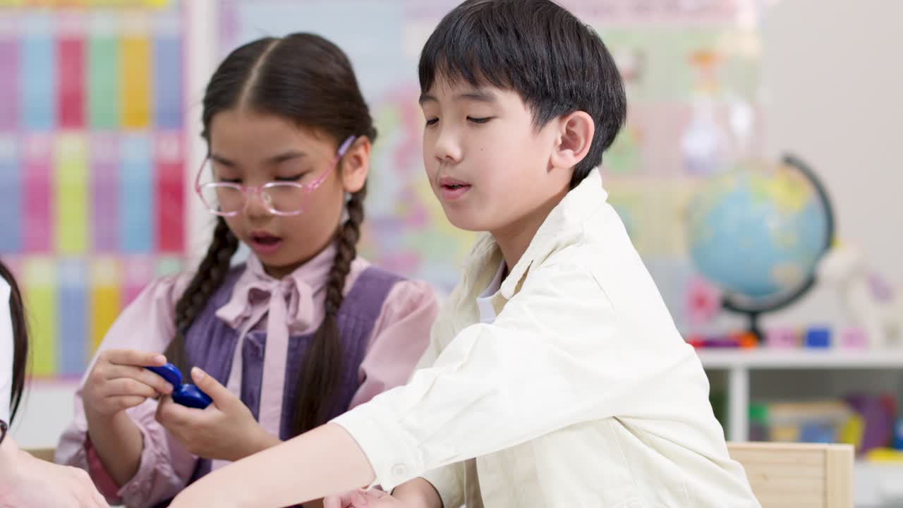 明るい教室で、3人の小学生がカラフルな磁石を使った実験を通して、遊び心のある共同作業で科学を学んでいます。