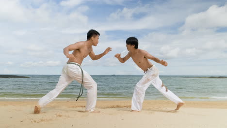 dos hombres bailando capoeira en la playa