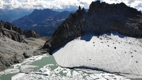 sobrevuelo aéreo sobre un lago glaciar lleno de icebergs derretidos en partes remotas de los alpes suizos en un día soleado con vistas panorámicas desde los picos de las montañas hasta la orilla del lago