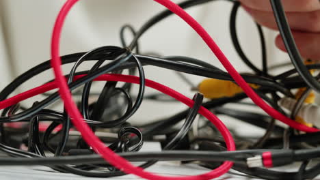 Young woman trying to untangle many various of wires close-up. Tangled wires and cables on table. Trying to untangle many messy and chaos cables