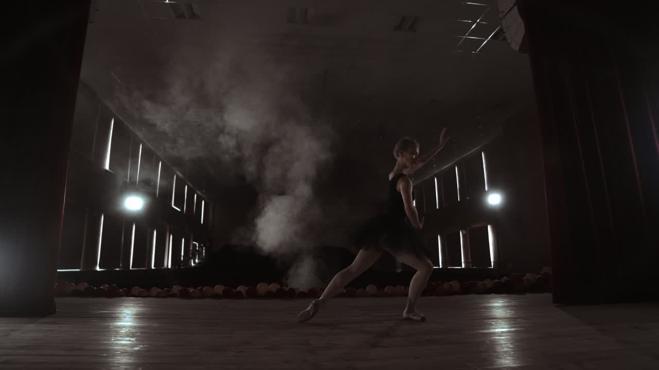 movimiento lento: prima ballet en el escenario ensayando la actuación en la luz oscura de la contra. las luces de la sala
