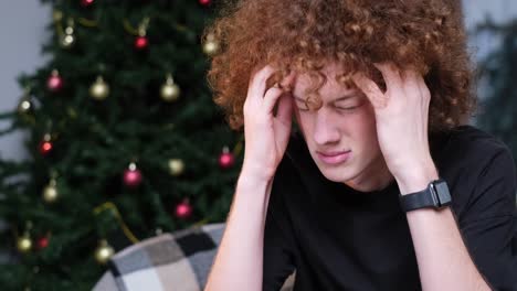 the young man is focusedly working behind his laptop he indicates that he has a headache the man i the young man is focusedly working behind his laptop he indicates that he has a headache the man is tired from work and he massages his temples with his hands