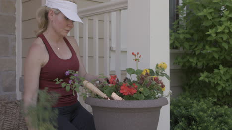 a woman is arranging flowers and plants in her flower pot on the front porch