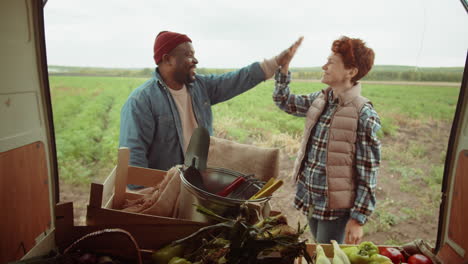 multiethnic farmers loading harvest in van and high fiving