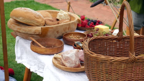 handwerkliches brot und käse mit fleisch auf einem holzplatt mit frischem obst, erinnert an ein rustikales mittelalterliches fest oder ein wikinger-piknik