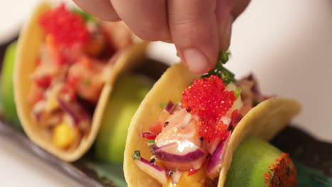 sushi tacos - chef garnishing the tacos with chopped onion chives