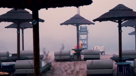 misty beach scene with umbrellas and lounge chairs