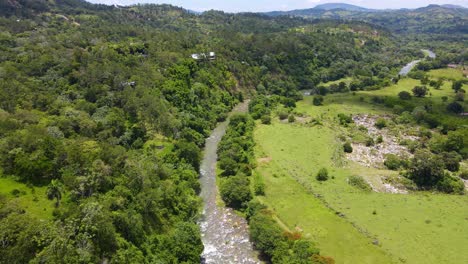 Rio-Yaque-del-Norte-with-a-forest-during-a-sunny-day,-surrounded-by-wildlife-and-mountains