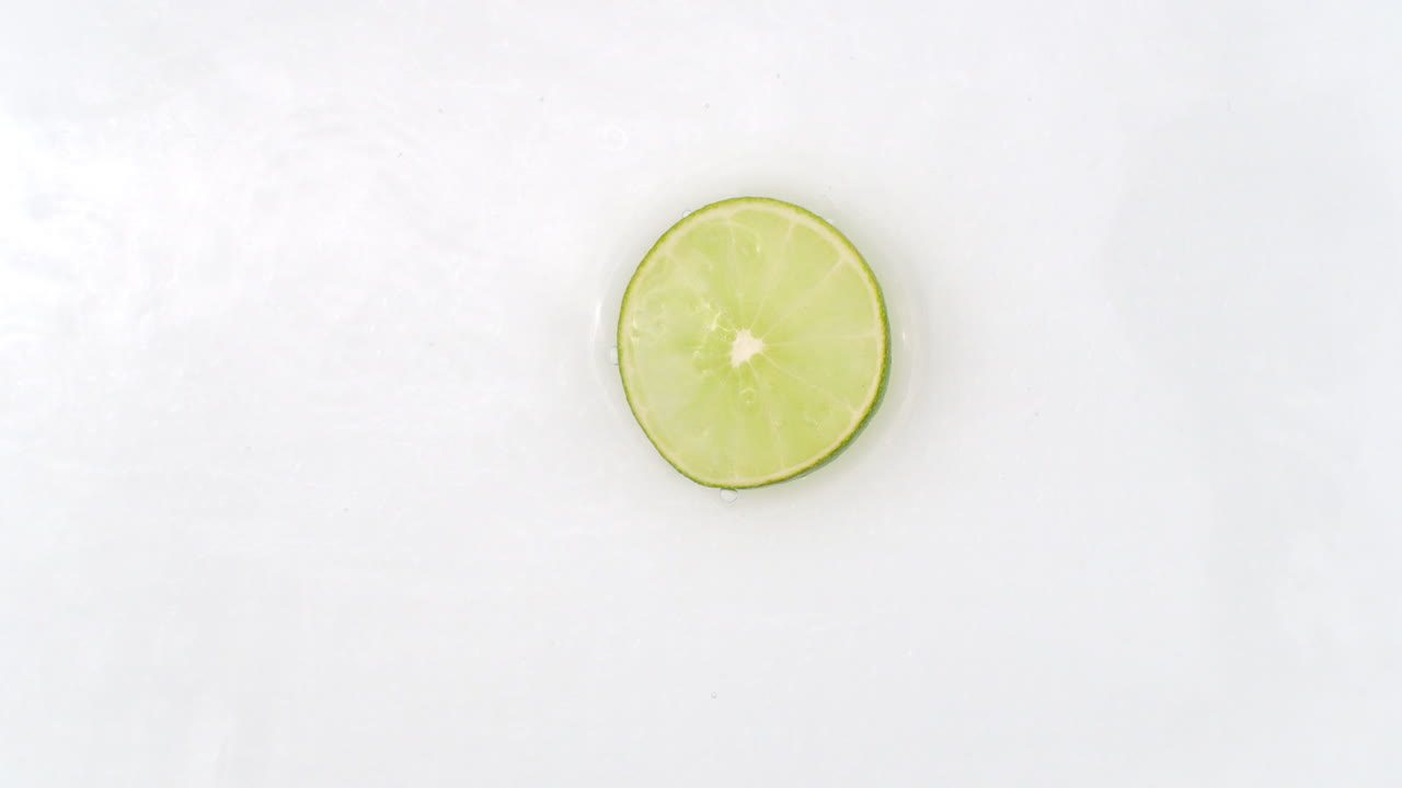 una cal yace en blanco en el fondo en cámara lenta cayendo salpicaduras de agua.