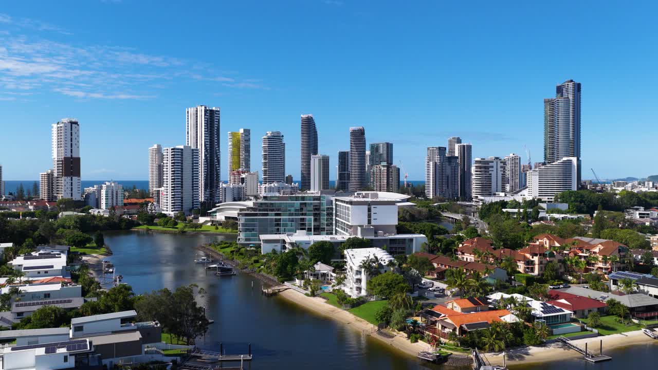 Aerial footage captures Gold Coast's skyline and waterways under clear blue skies, showcasing urban architecture and natural beauty