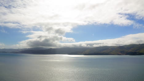 sunny glare on water with rolling hills and clouds