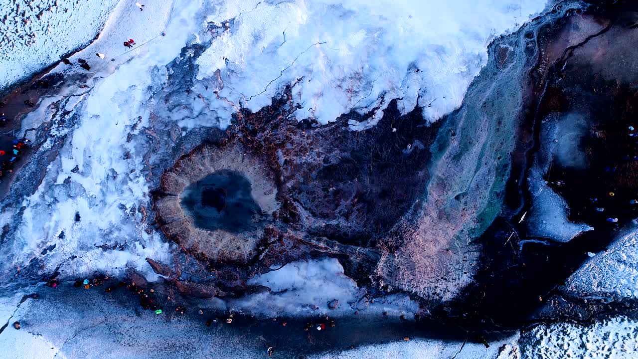 아이슬란드의 게이시르에 있는 게이저 위의 아름다운 공중 풍경: 이 게이저 밖으로 어나오고, 사람들이 해가 지는 곳에서 게이저를 둘러싸고 산책하고 있다.