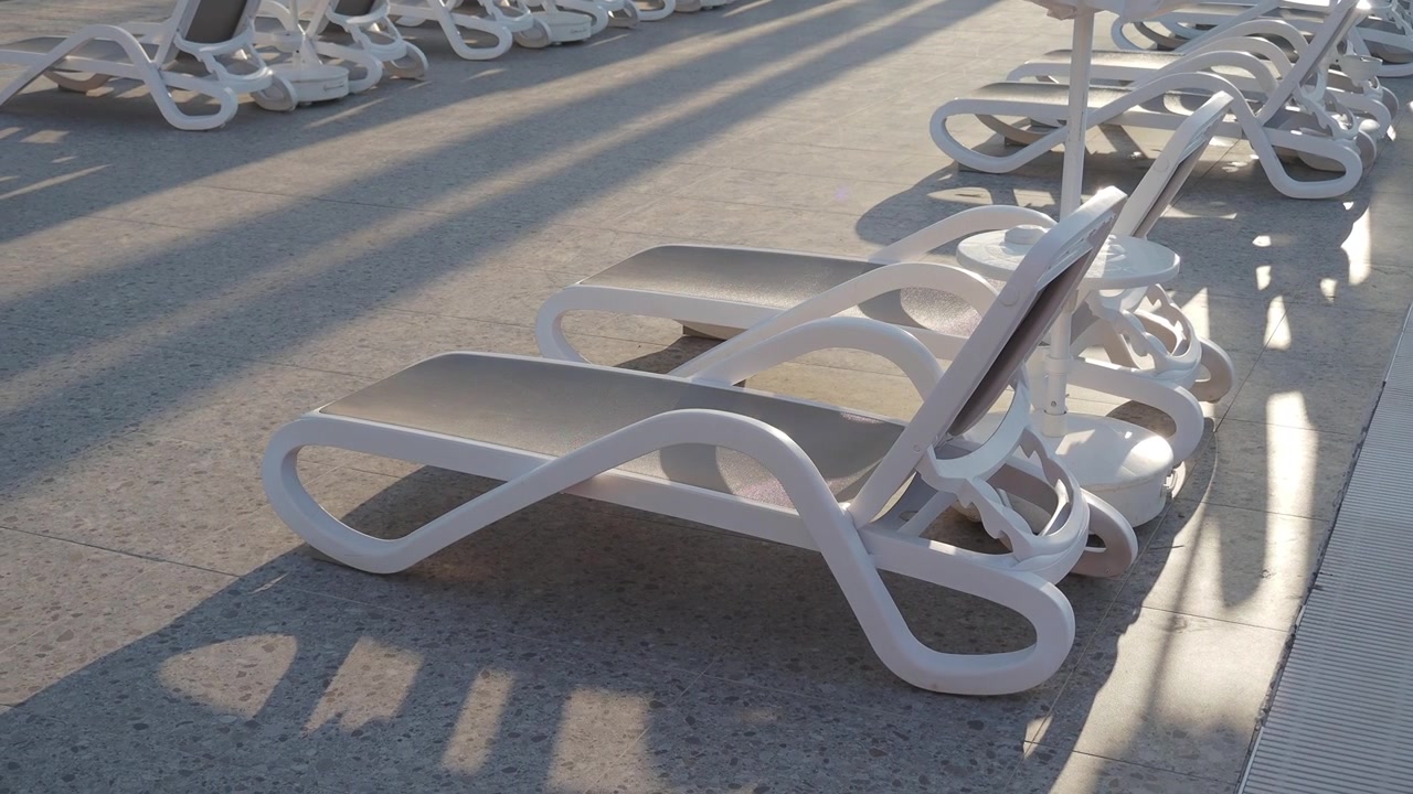 Empty Sun Loungers by a Swimming Pool at Sunset