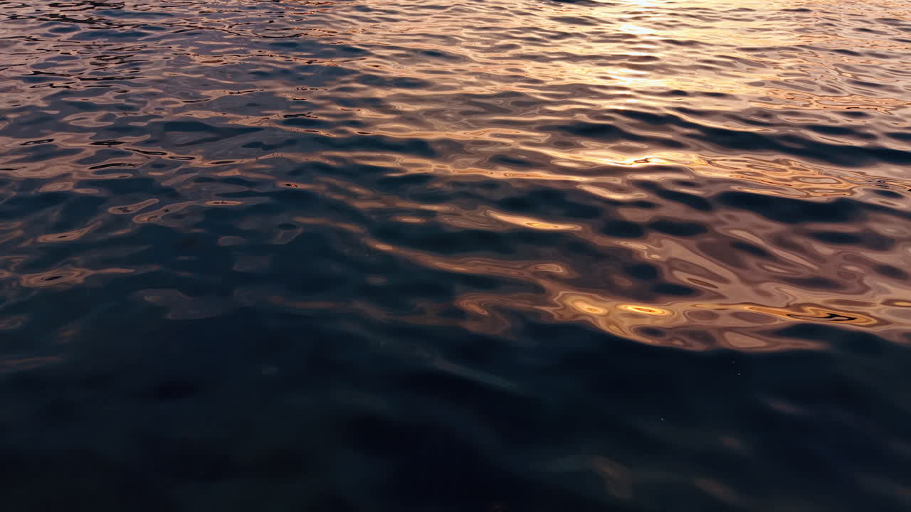 Deep blue waterscape colored with setting sun. Seascape background from top view