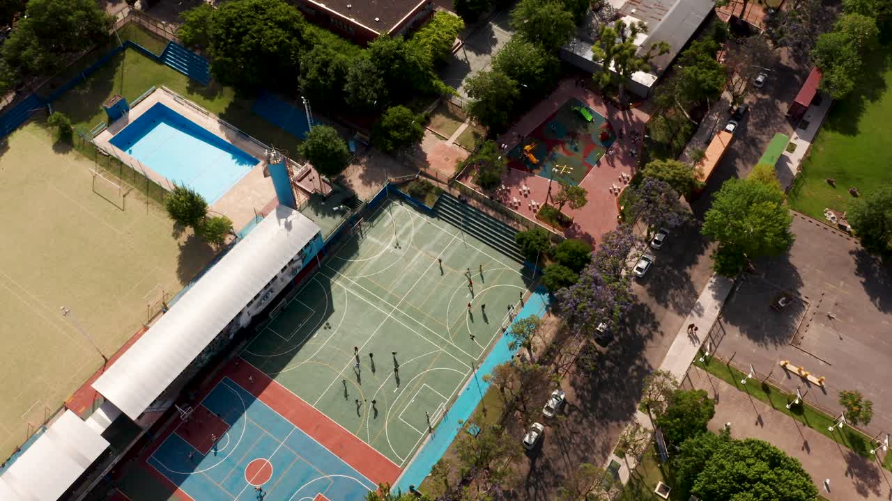 Personas atléticas jugando baloncesto y fútbol en una zona recreativa bajo la luz del sol.