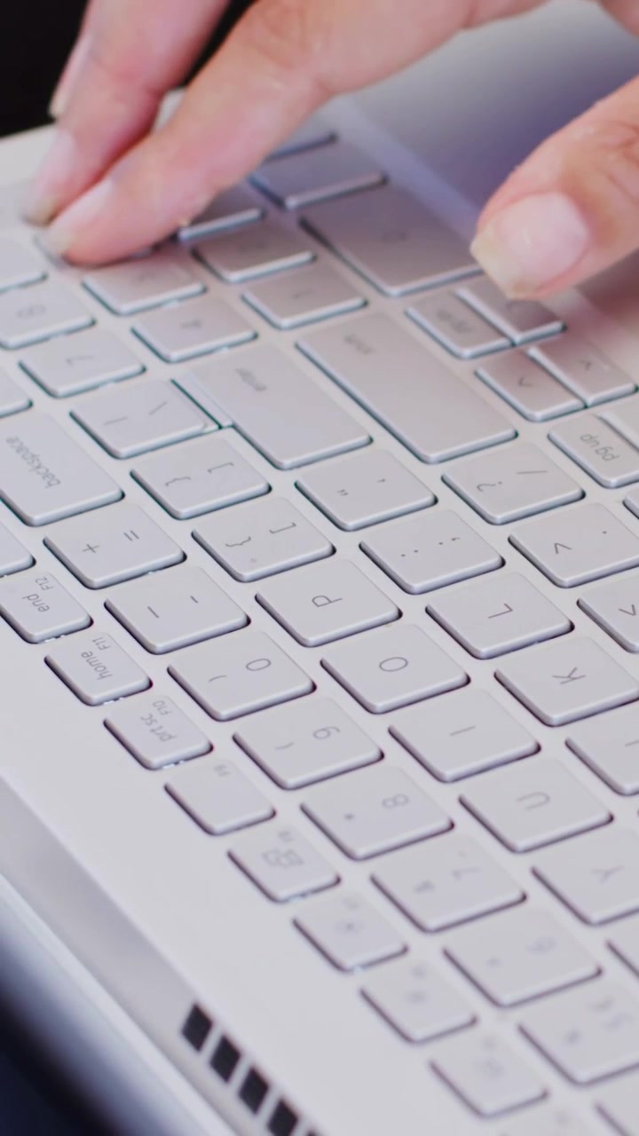 Vertical video: Starting task, adult hands moving across laptop keyboard on lap tapping trackpad
