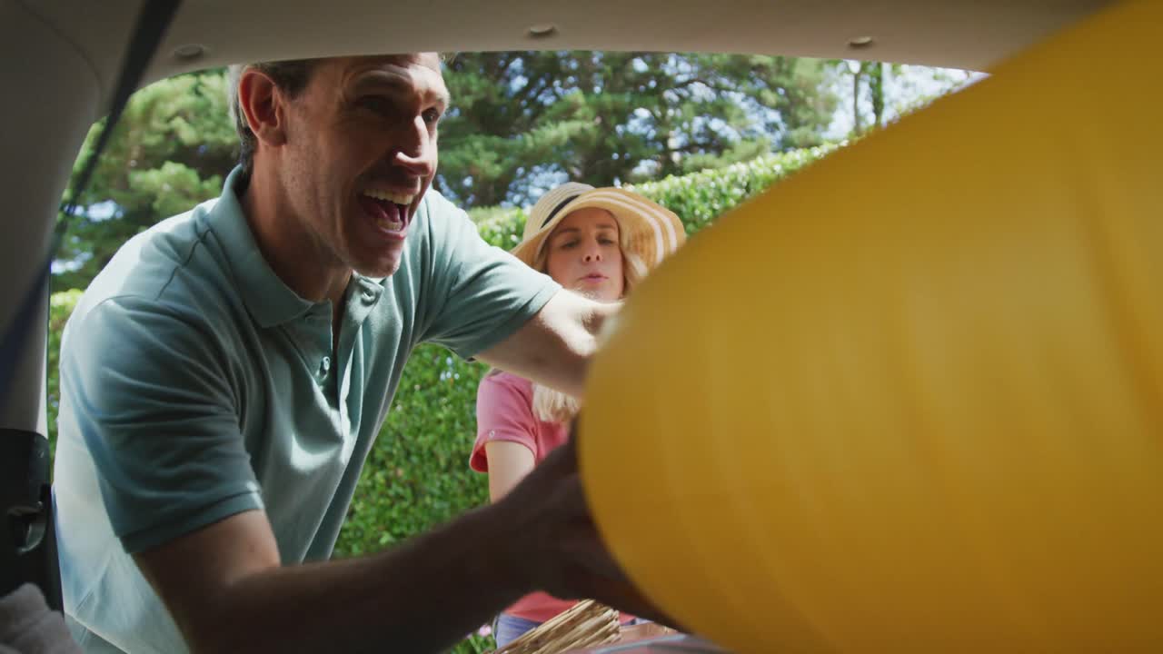feliz pareja caucásica con hijo empacando el coche y preparándose para las vacaciones