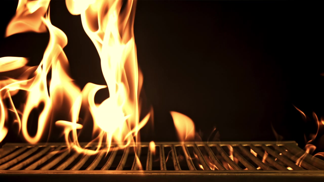Griglia rovente con fiamme ardenti su sfondo nero.