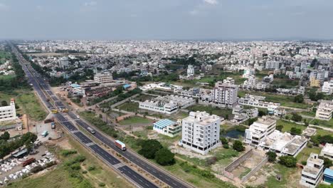 aerial drone shot of highway passing through busy city in india with blue sky