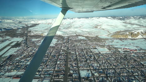 flying in small airplane above snow capped gunnison town, colorado usa, getaway to crested butte mountain resort and maroon bells peaks