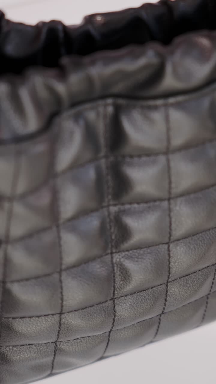 A close-up of a ruched drawstring top made of quilted black ecological leather, highlighting its soft, glossy texture and fine stitching details.