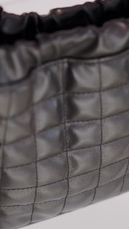 a close-up of a ruched drawstring top made of quilted black ecological leather, highlighting its soft, glossy texture and fine stitching details.