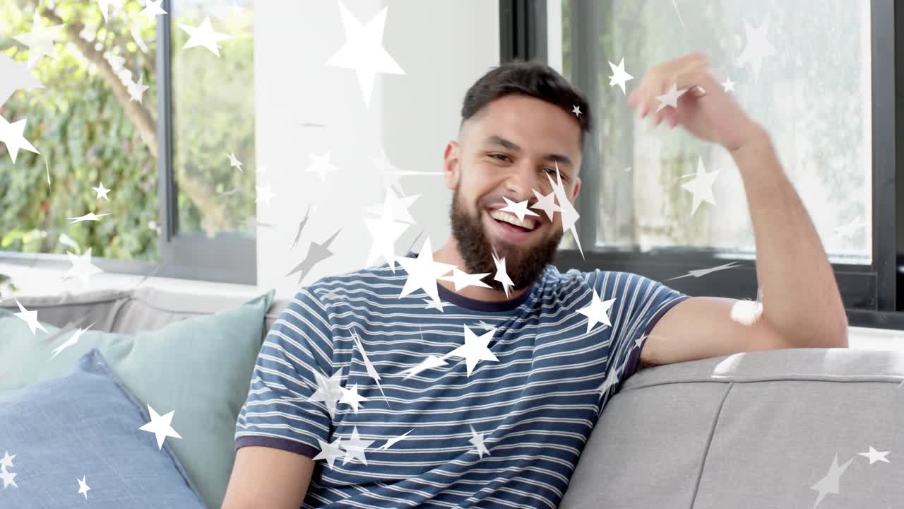 Man reacting to off-camera cue, turning and laughing on grey sofa with star overlay for marketing