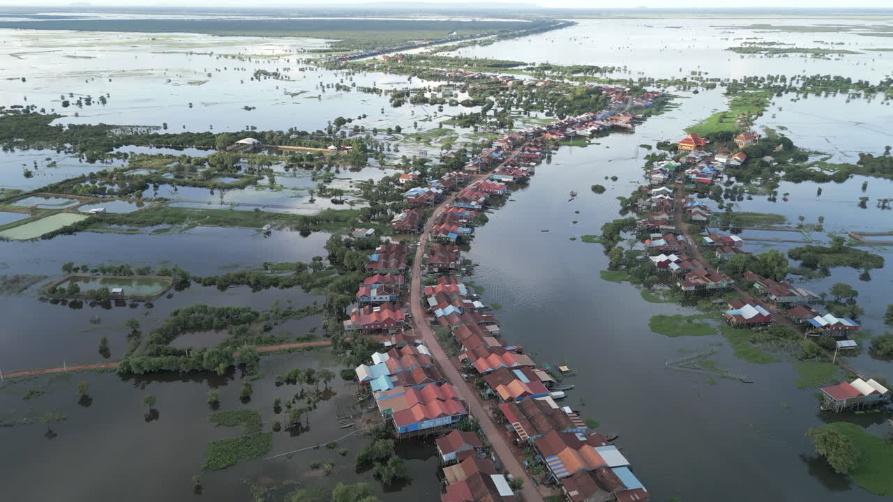 Aerial video shows a flooded road lined with stilt houses in Tonlé Sap, surrounded by wetlands and boats